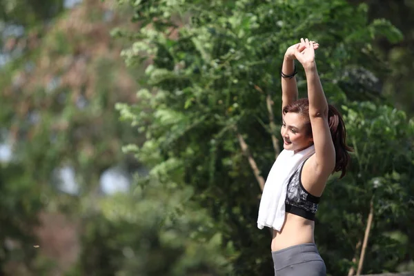 Fitness runner body closeup doing warm-up routine before running, stretching arm muscles with standing single, Female athlete preparing legs for cardio workout.