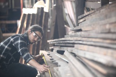 Marangoz, atölyede çalışıyor. Tahta üzerinde çalışan bir adam. Atölyedeki olgun marangoz imajı, mobilya yapma konsepti..