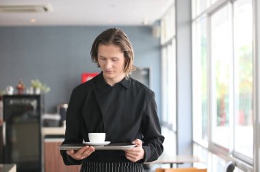 Yakışıklı bir erkek barista kahve dükkanında çalışıyor.
