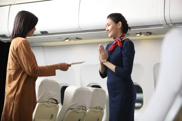 Air hostess or stewardess service , Young slim and atractive woman stewardess and background of plane, Asian flight attendant posing with smile at middle of the aisle inside aircraft passenger seat