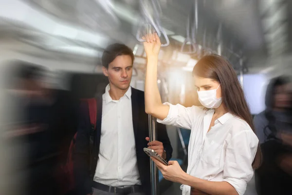 People with masks inside train , People on the train wear anti-virus masks and travel during rush hours. passengers inside the Sky Train , business people standing in metro mass transit subway.