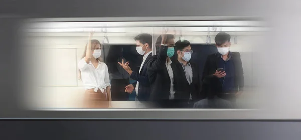 People with masks inside train , People on the train wear anti-virus masks and travel during rush hours. passengers inside the Sky Train , business people standing in metro mass transit subway.