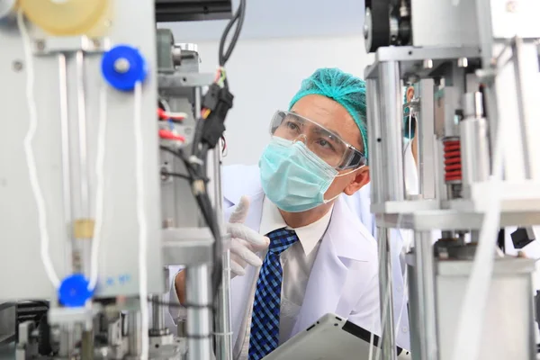 Production engineer with face mask working in factory , Qc engineer checking mask for good quality , Concept of protective action and quarantine to stop spreading of Coronavirus Disease 2019