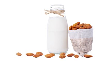 İzole edilmiş süt ve badem. Beyaz arka planda kenevir kumaş torbasında badem bulunan cam süt şişesi. Ev yapımı badem sütü. Kopyalama alanı ve kırpma yolları ile.