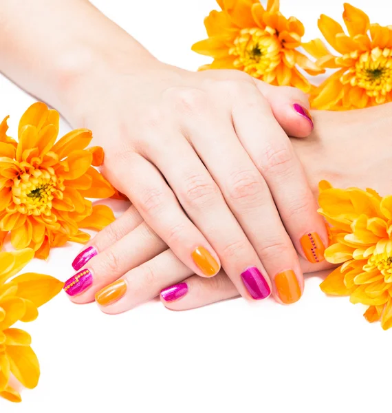 Mãos de mulher com manicura brilhante e flores em volta — Fotografia de Stock