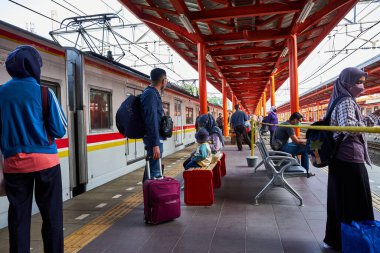 Tren istasyonunda bir banliyö treninin yanında bekleyen gezginler..