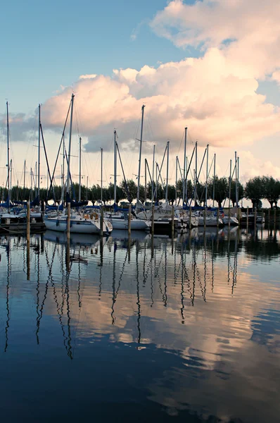 Riflessione di barche a vela, nuvole e alberi in acqua Foto Stock