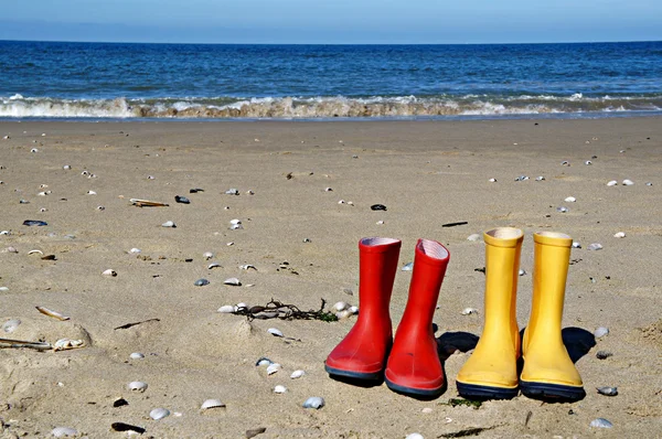 Red and yellow rain boots on the beach