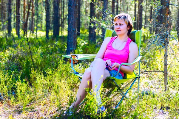 Γυναίκα συλλογισμένος κάθεται σε μια καρέκλα στο δάσος. — Φωτογραφία Αρχείου