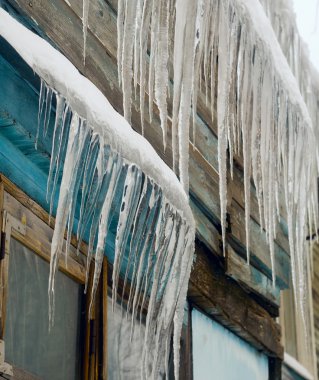 Uzun buz sarkıtları evin çatısından asılı.