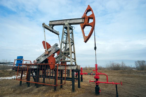 Bomba mecedora en un campo de petróleo en la primavera . —  Fotos de Stock