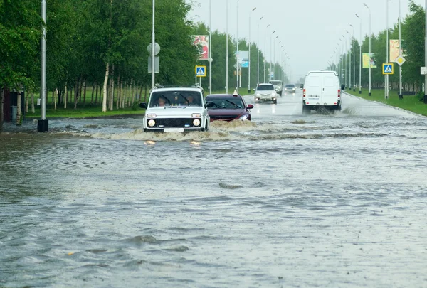 Şehirde sokakta büyük bir su birikintisi geçiş araçları.