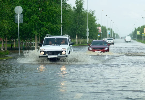 Автомобілі перетинають величезну калюжу на вулиці міста . — стокове фото