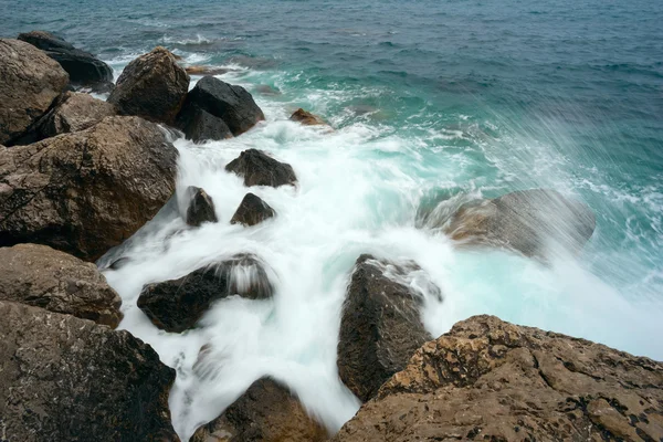 Taşlı bir kıyıda kırma dalgalar deniz — Stok fotoğraf