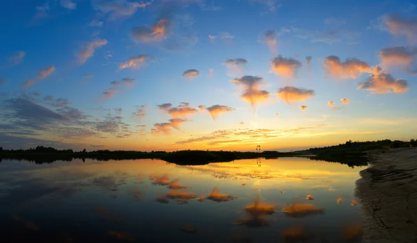 Des nuages volent au-dessus de l'eau au coucher du soleil . — Photo