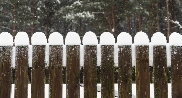 Snow caps on top of a wooden fence