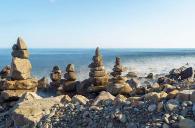 Deniz kenarındaki deniz taşları piramitleri. Denize giriş.