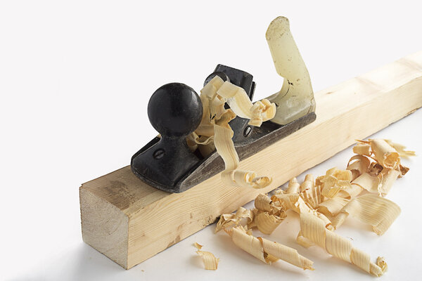 Old iron planer on a wooden bar with chips on white background