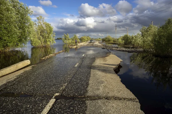 Seção inundada de estrada com asfalto quebrado — Fotografia de Stock