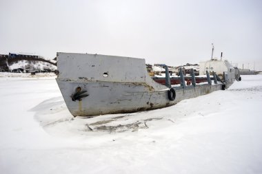 Terk edilmiş balıkçı teknesi donmuş bir nehir.