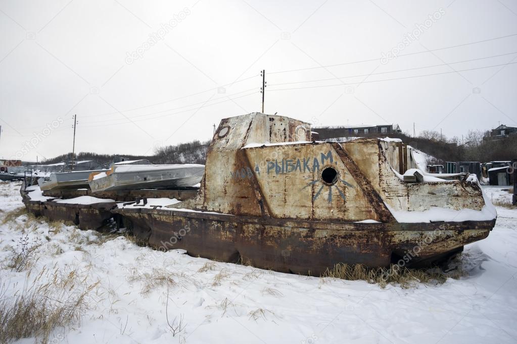 Old fishing boat on the shore in  winter.