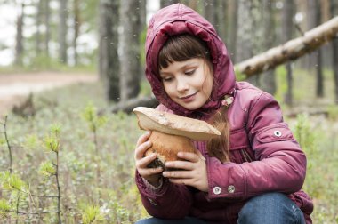 Bir ormandaki mutlu kız büyük mantar görür .