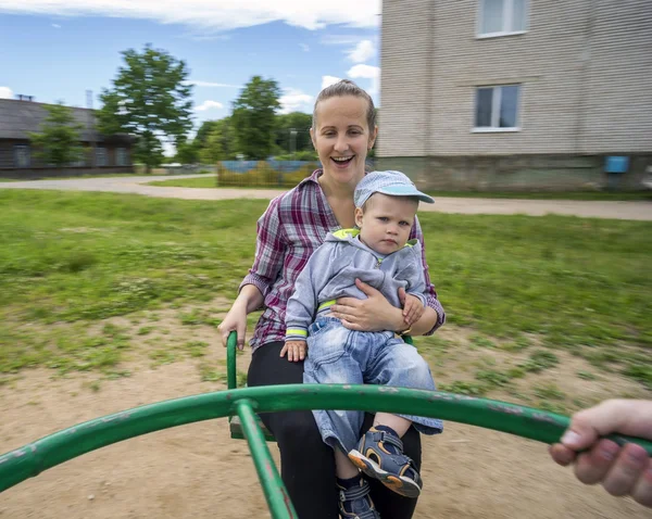 Jonge moeder met haar zoon 1.3 jaar rijden op carrousel. — Stockfoto