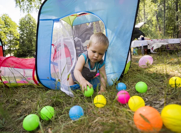 De jongen 1.3 jaren zorgvuldig spelen met kleurrijke ballen in Kinder tent op groen gras Park. — Stockfoto