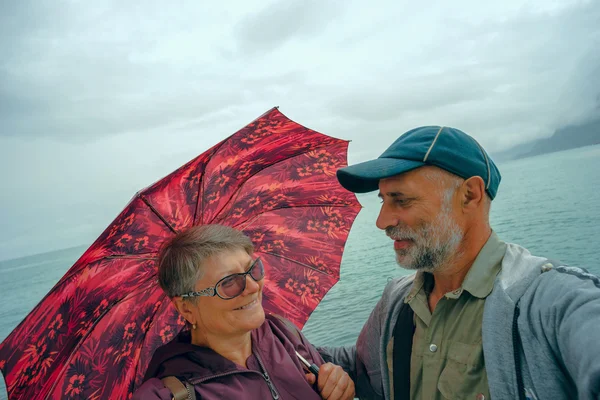 Frau unter einem Regenschirm und Mann mit Liebe schauen einander an . — Stockfoto