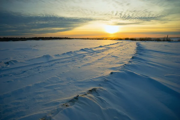 Coucher de soleil lumineux hiver avec route et empreintes de pas dans la neige . — Photo