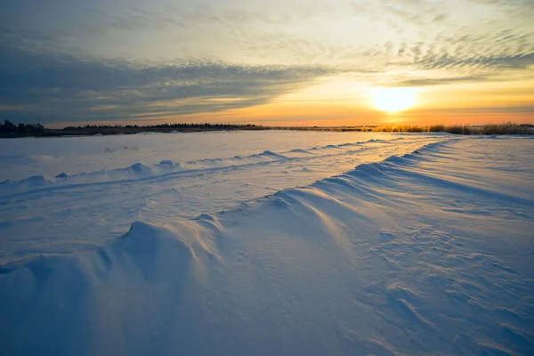 Felle zon zonsondergang winter met weg- en voetstappen in de sneeuw. — Stockfoto