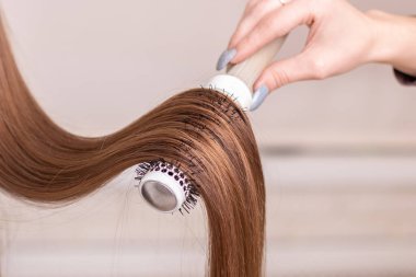 Kuaförün eli, kuaförde uzun, esmer saçları tarıyor.