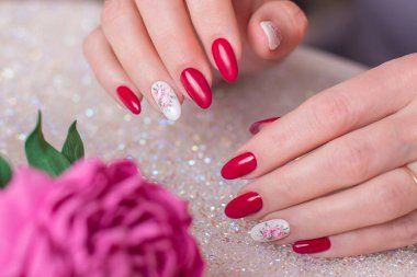 Romantik manikür tırnakları, pembe jöle cilası, şakayık çiçekleri tasarımı olan güzel kadın ellerinin yakın görüntüsü