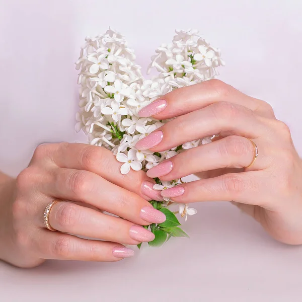 Düğün manikürlü güzel kadın elleri, pembe jel cilası ve beyaz çiçekler.