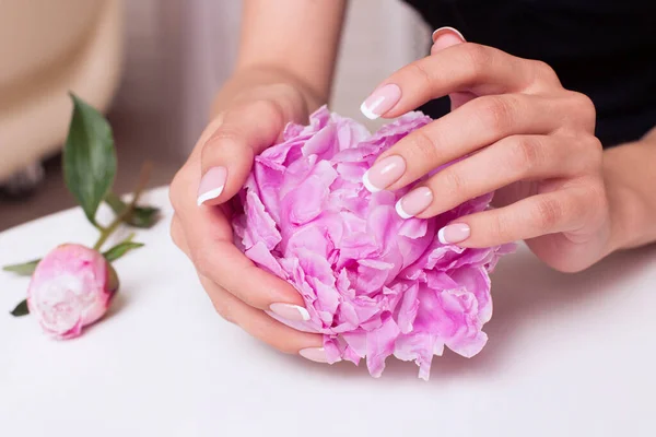 Gelin manikürlü güzel kadın elleri, pembe beyaz jöle cilası, şakayık çiçekleri.