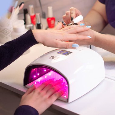 Manikür tırnaklı bir kadın. Güzellik salonunda jöle lambasında.