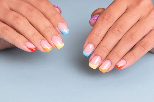 Beautiful female hands with colourful manicure nails with rainbow design