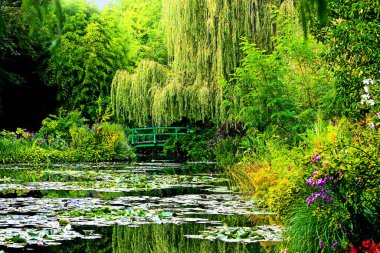 Claude Monet 'nin Fransa' daki Giverny Bahçesi 'ndeki nilüfer göletine yansıyan yeşil Japon köprüsü.