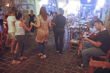 Chania, Creet Adası, Yunanistan / Fotoğraf: Chania caddesinde yerel müzik sanatçıları Chania, Girit Adası, Yunanistan 'daki bir restoranın önünde dans eden bilinmeyen kişiler  