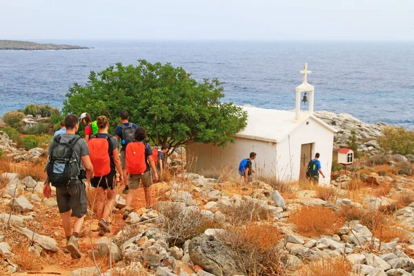 Young People hiking near an small church on a path in Crete island, Greece