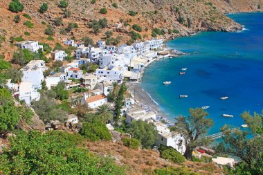 Small sail and fisher boats anchored in Loutro with pristine blue water and traditional white buildings, taverns and restaurants, Loutro, Crete, Greece clipart