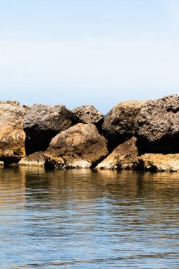 Deniz ve kaya arka planı. Kaya ve mavi deniz, berrak gökyüzü. Sahil seyahati hedef arkaplan resmi. Yazın açık mavi deniz ve mavi gökyüzü