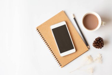 Akıllı telefon, defter, kalem, kahve ve fotokopi arkaplanı olan kuru çam kozalaklı ofis masasının düz bir fotoğrafı..