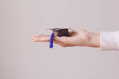 Beyaz arka planda el ele mezuniyet şapkası.