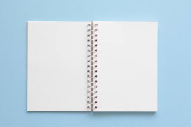 Mavi pastel arka plan üzerine boş bir defter. En az stil.
