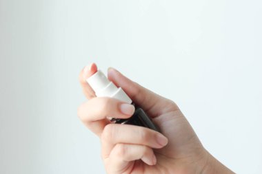 Beyaz arka planda ağız spreyi tutan kadın. Ağız ve diş bakımı