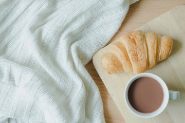 Masada bir fincan kahveyle kruvasan manzarası.