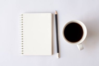 Kağıt defter, kalem, beyaz arka planda bir fincan kahve. Ofis masaüstü görünümü. En düşük biçim.