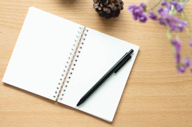 Ahşap masadaki kalemli defterin üst görünümü.