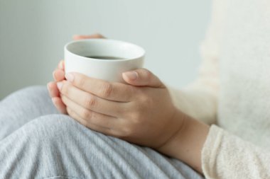 Kadın evde oturup sıcak kahve içiyor ve sabah keyfine bakıyor, rüya gibi ve rahat bir ruh hali içinde..